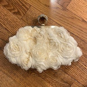 Cream colored clutch by INC with fabric roses covering the exterior.